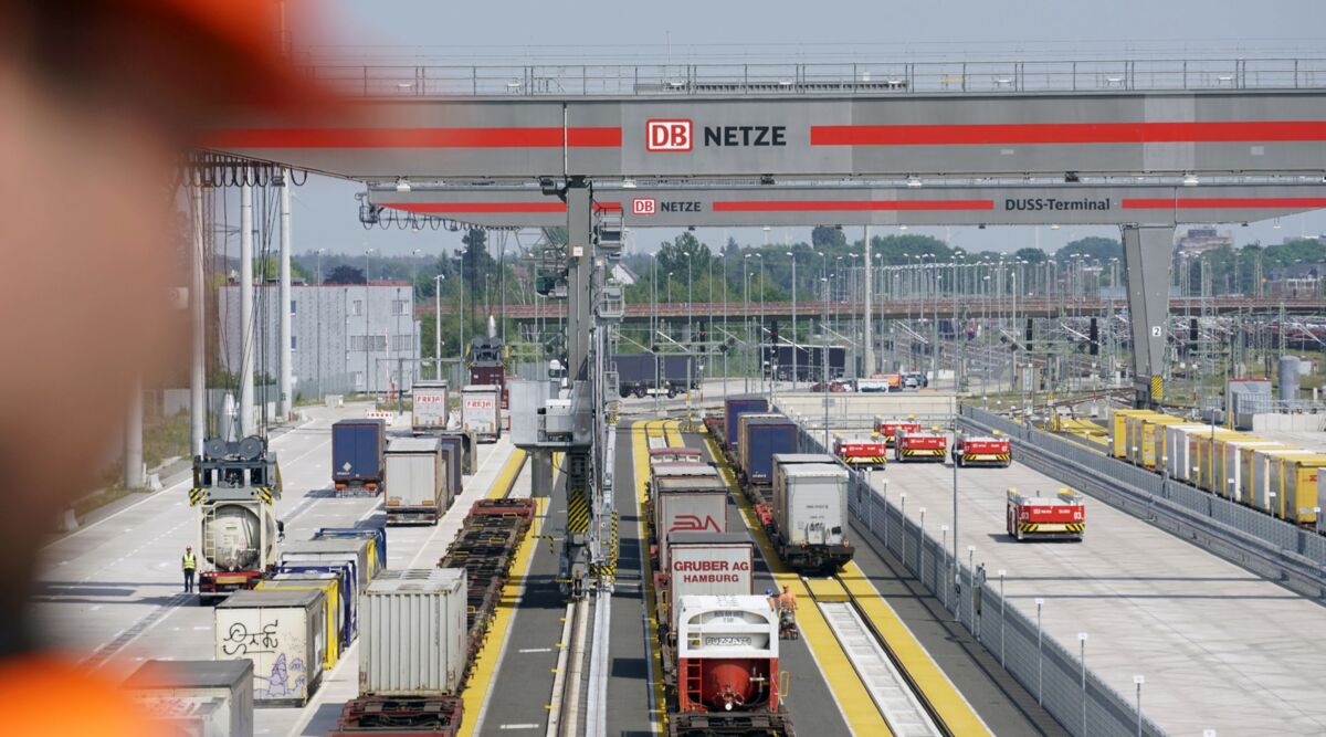 Ausblick auf das KV-Terminal bei Tag mit Containerkranen, Containern und Fahrzeugen.
