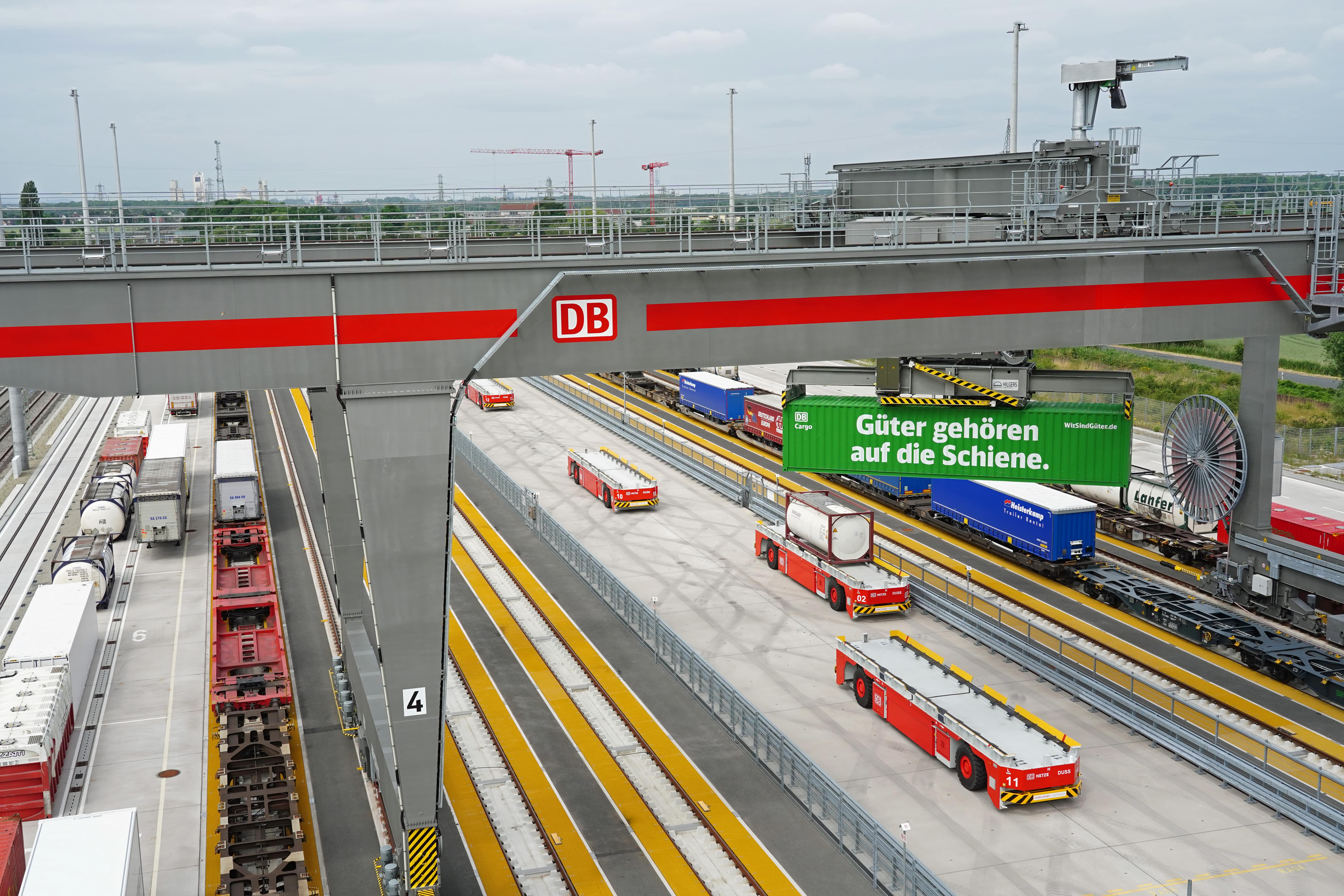 Vogelperspektive auf Containerkran, Umschlagplatz und selbstfahrende Fahrzeuge.