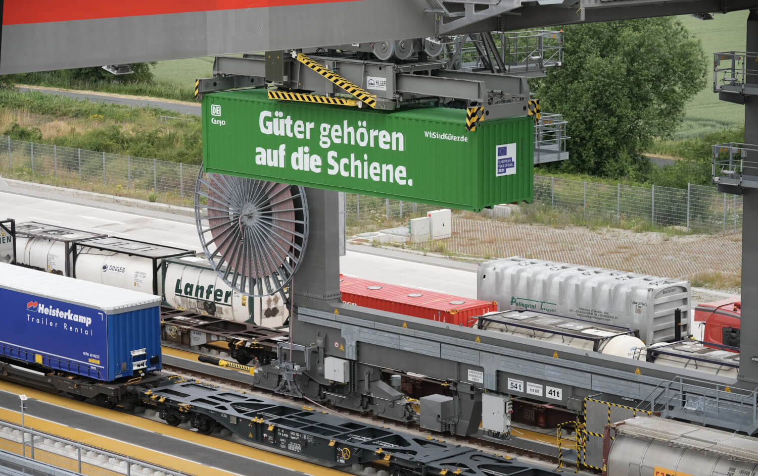 Umschlagbahnhof mit einem grünen Container. Text auf Container: Güter gehören auf die Schiene.